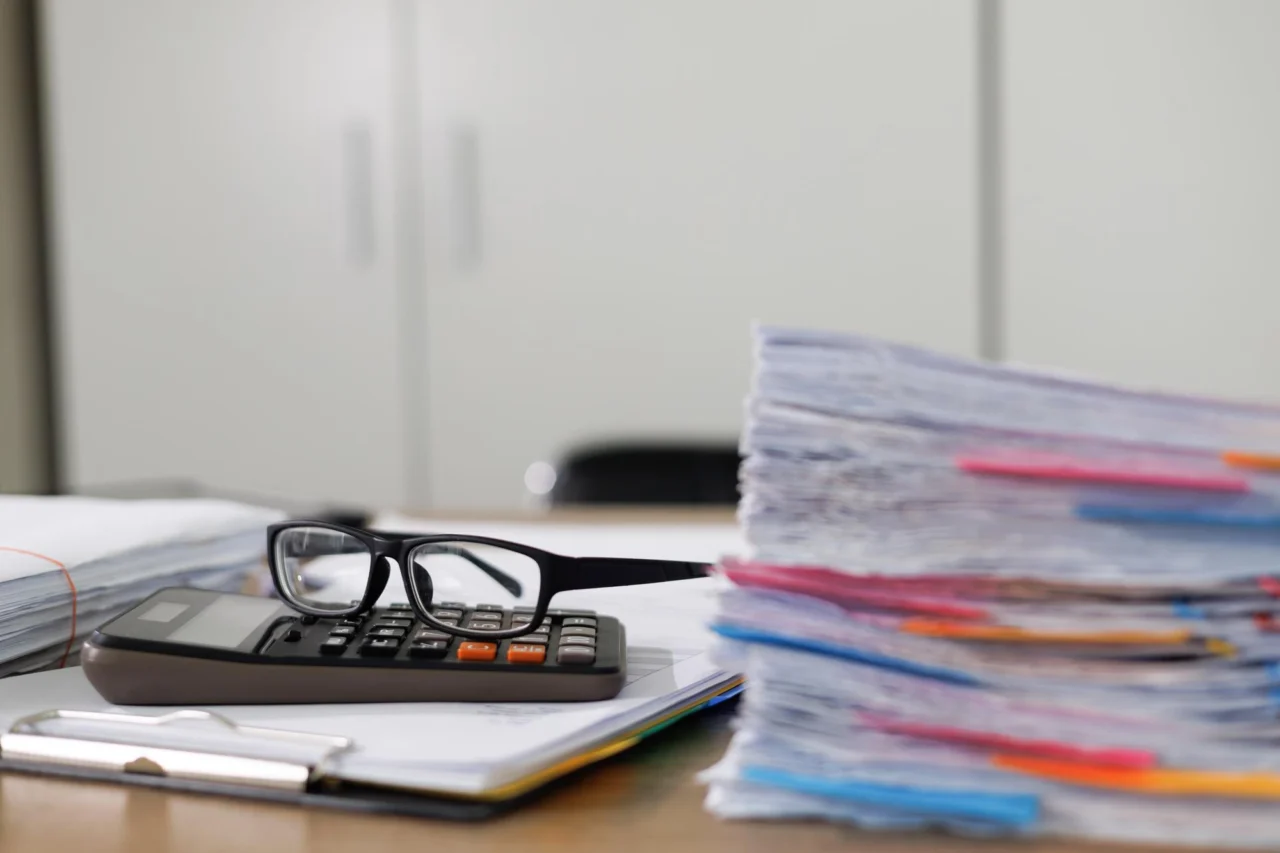 A stack of company files and paperwork on an office desk
