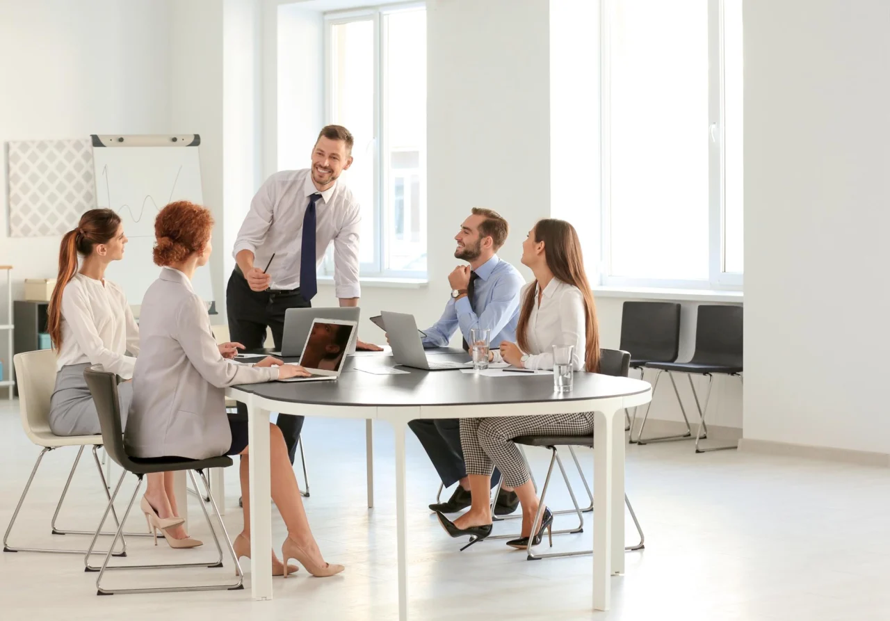 A team meeting around a round table in a bright open-plan office