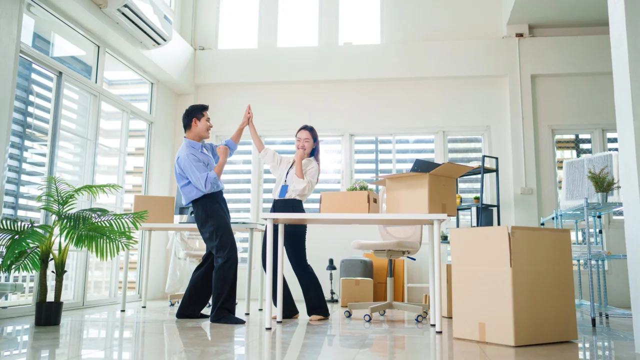 Colleagues celebrating with a high five in a new office among moving boxes