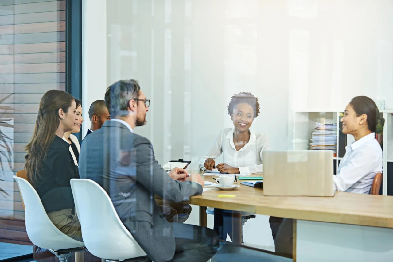 A management team meeting around a table in a glass-walled boardroom